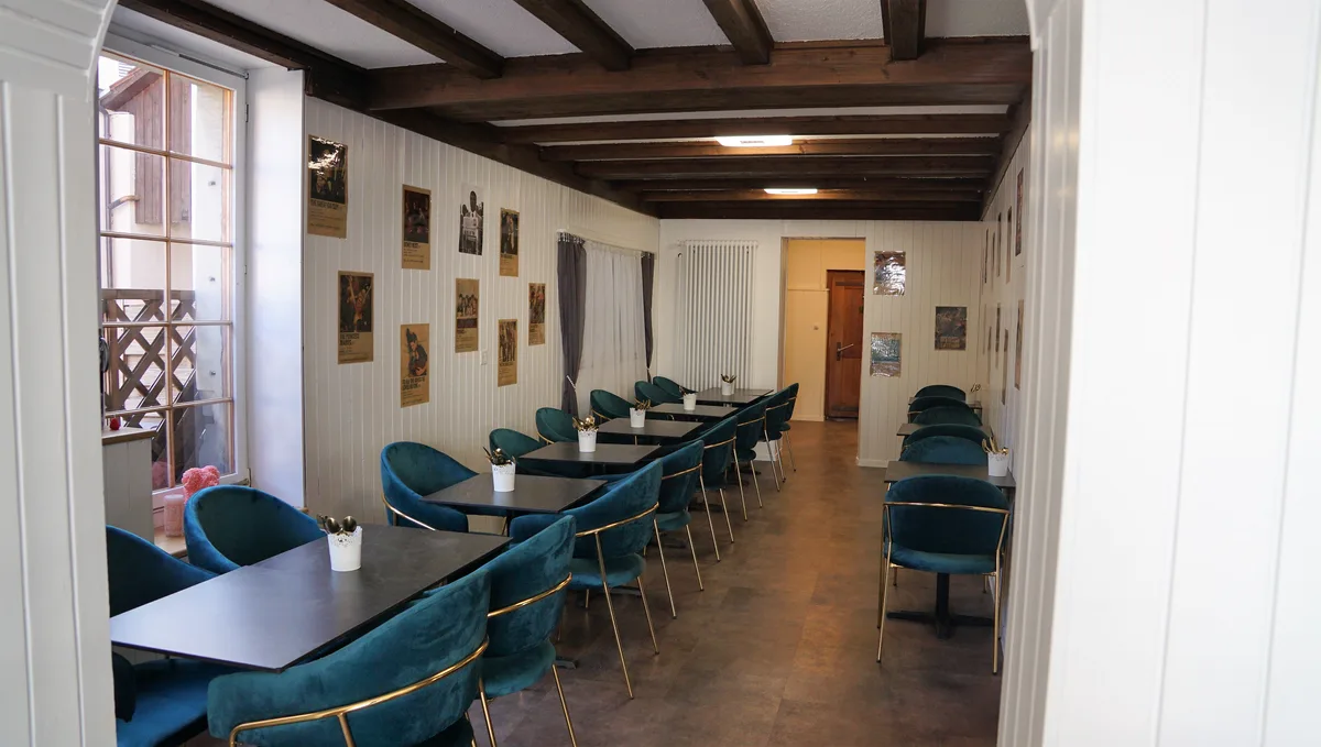 Man sieht den Innenraum eines Cafés mit Tischen und Stühlen.